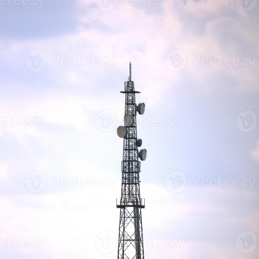 Radio tower and clouded sky, bearing dishes. photo