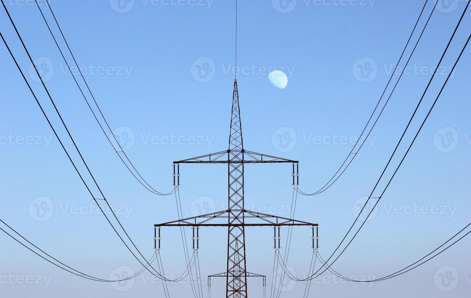 Symmetrical view on a high voltage power line The moon is visible in the background photo