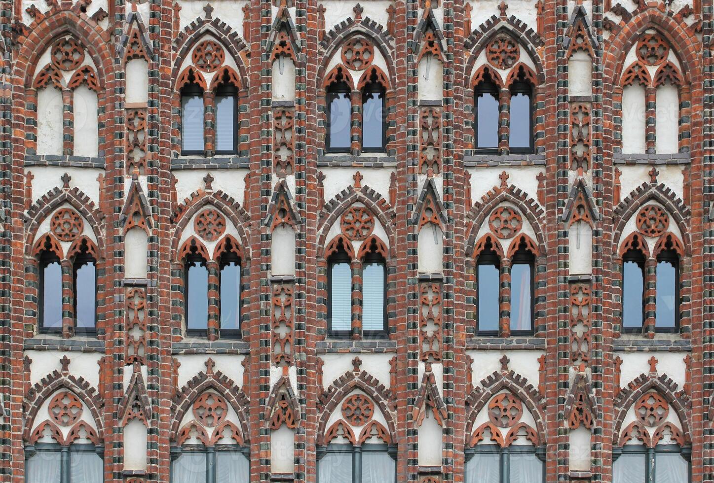 Facade of a historic city center building in the style of brick gothic with many windows. This architectural style was used from the 12th to the 16th century. photo