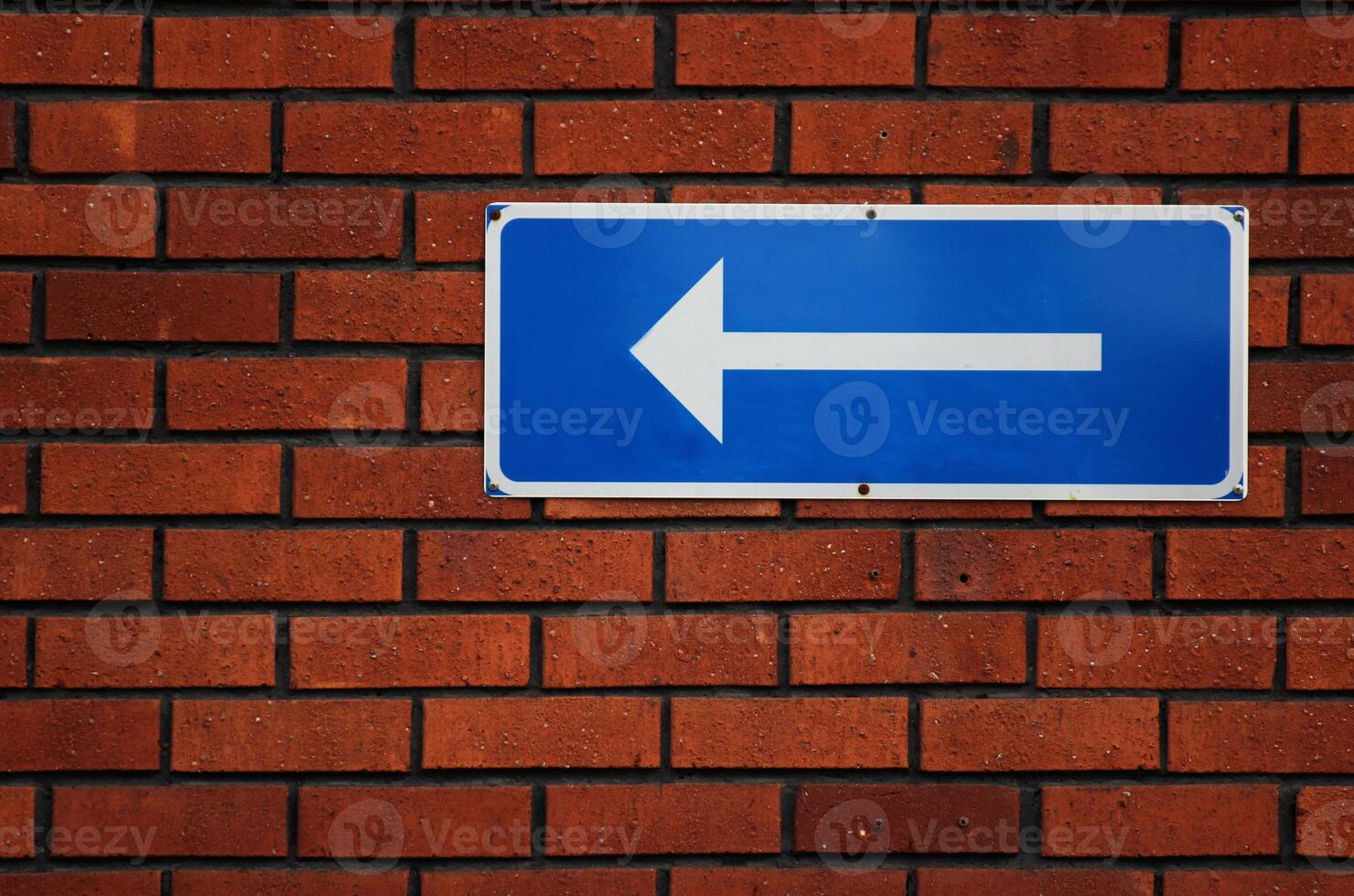 Arrow sign on a red brick wall. photo