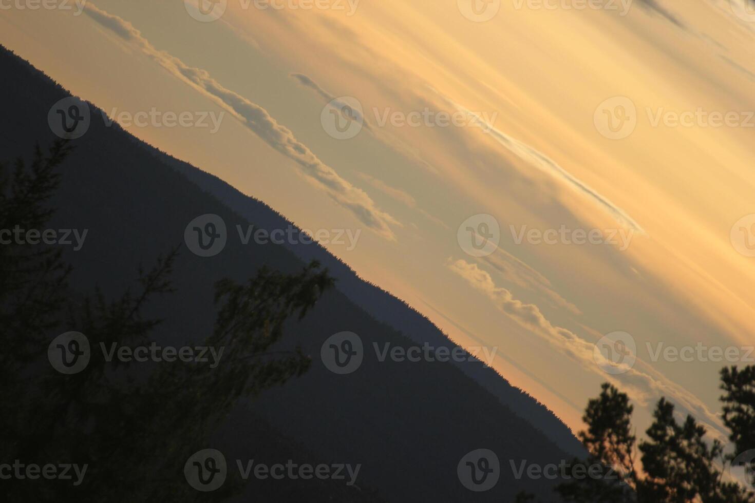 Sky with different shades of orange over a mountain silhouette in Sweden in unusual angle. photo