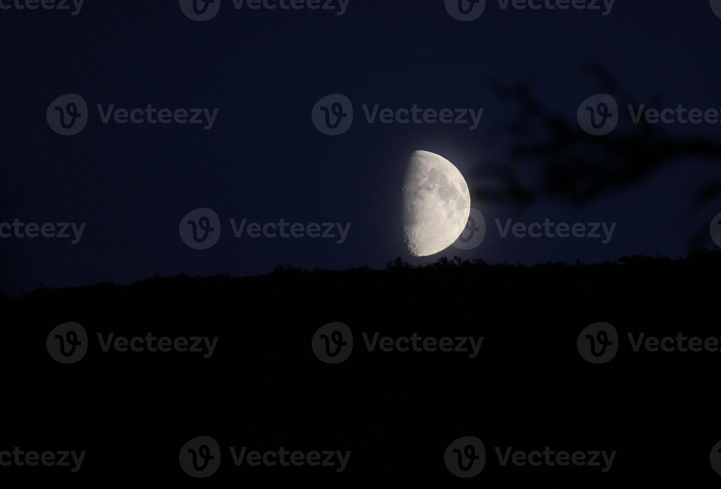 Partial moon on dark blue with slightly visible horizon. photo