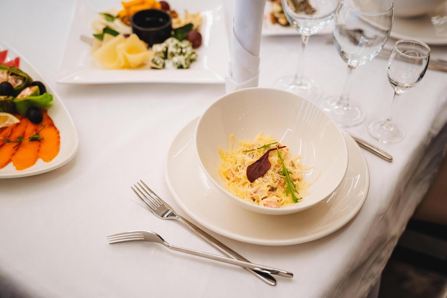 A beautifully arranged table featuring a variety of plates filled with delicious food items, along with an assortment of utensils such as forks, knives, and spoons ready for use photo