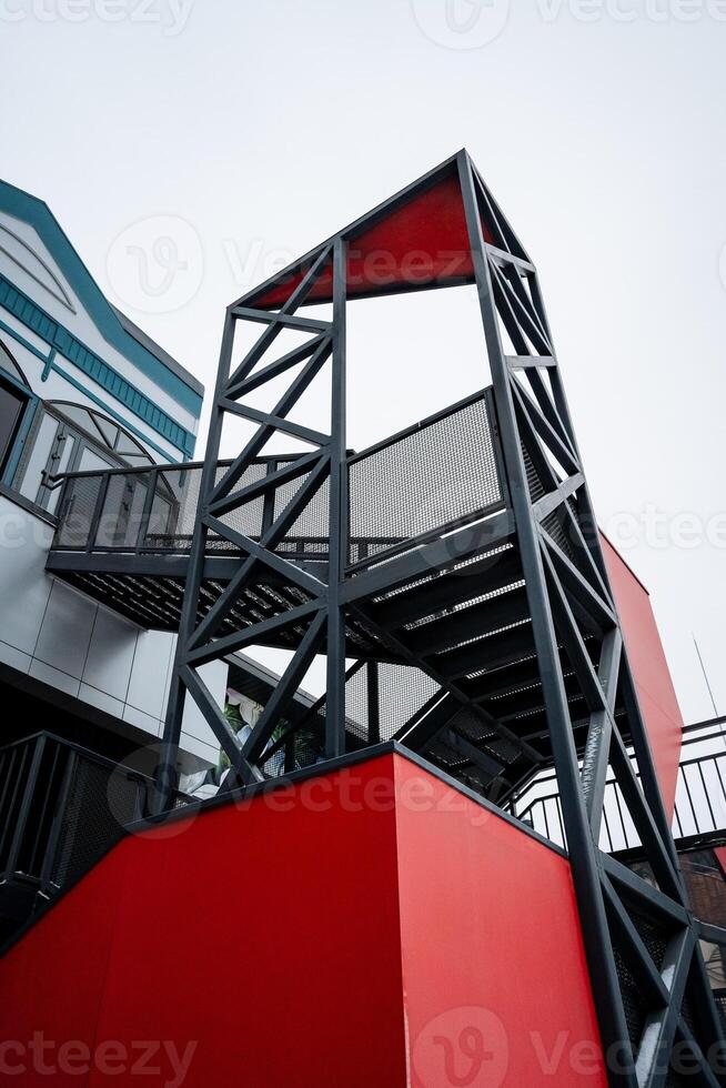 A vibrant red and black staircase leads to a contemporary building that merges innovative engineering with stunning design, showcasing a perfect balance of materials and aesthetics photo