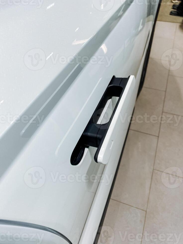 In the parking lot, a pristine white car with an elegant black door handle showcases a captivating blend of colors, reflecting modern automotive design and sophistication photo