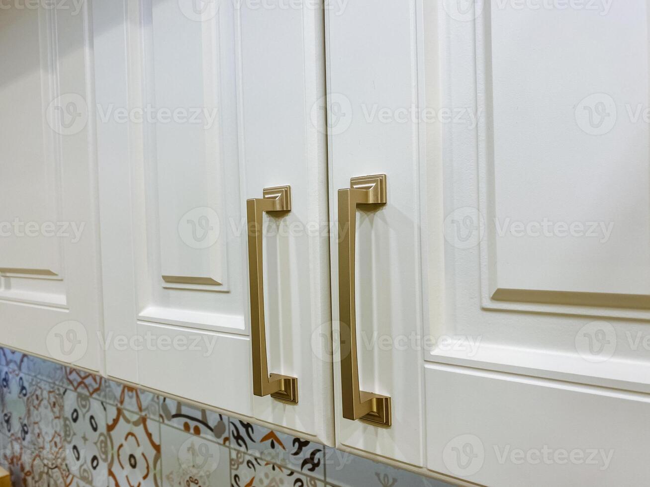 This is a close up view of a beautifully designed kitchen cabinet featuring elegant gold handles that add a touch of sophistication and style to the overall decor of the kitchen photo
