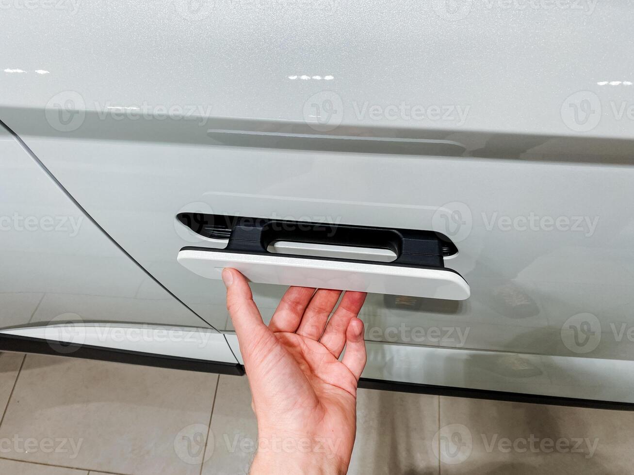 A person is using their hand to open the door of a car, demonstrating a simple yet significant action that showcases the interaction with automotive design and functionality photo