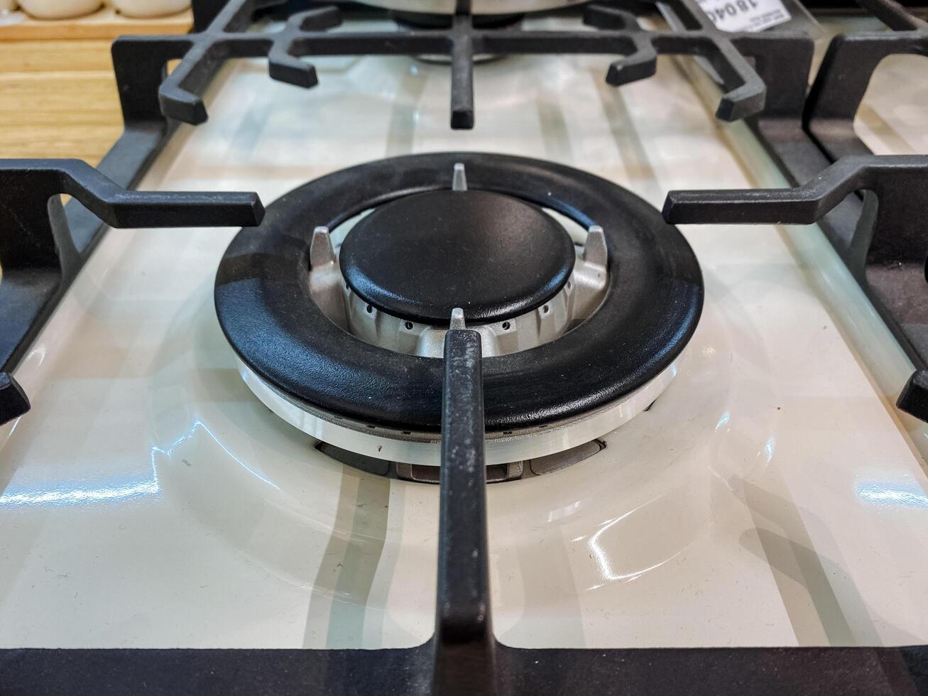 This is a closeup image of a modern gas cooktop burner, showcasing a detailed control knob along with strong metal grates, all set within an elegantly designed kitchen space photo