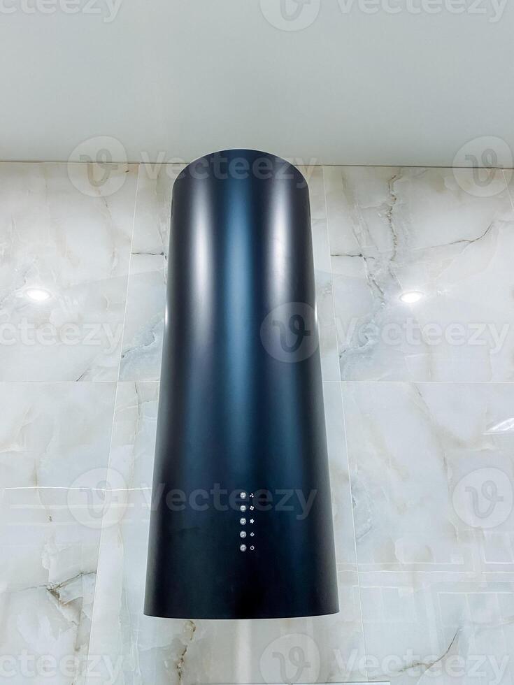 A black hood is elegantly hanging down from the ceiling in a modern kitchen, creating a visually appealing element that complements the overall decor and functionality of the space photo