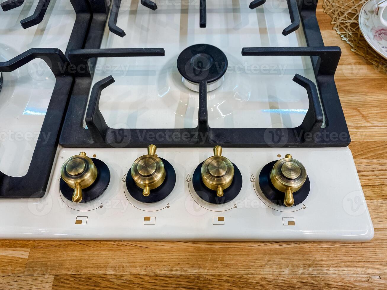 A classic gas stove that features four burners is currently placed on a sturdy wooden counter, highlighting its functionality and the beauty of natural wood in the kitchen environment photo