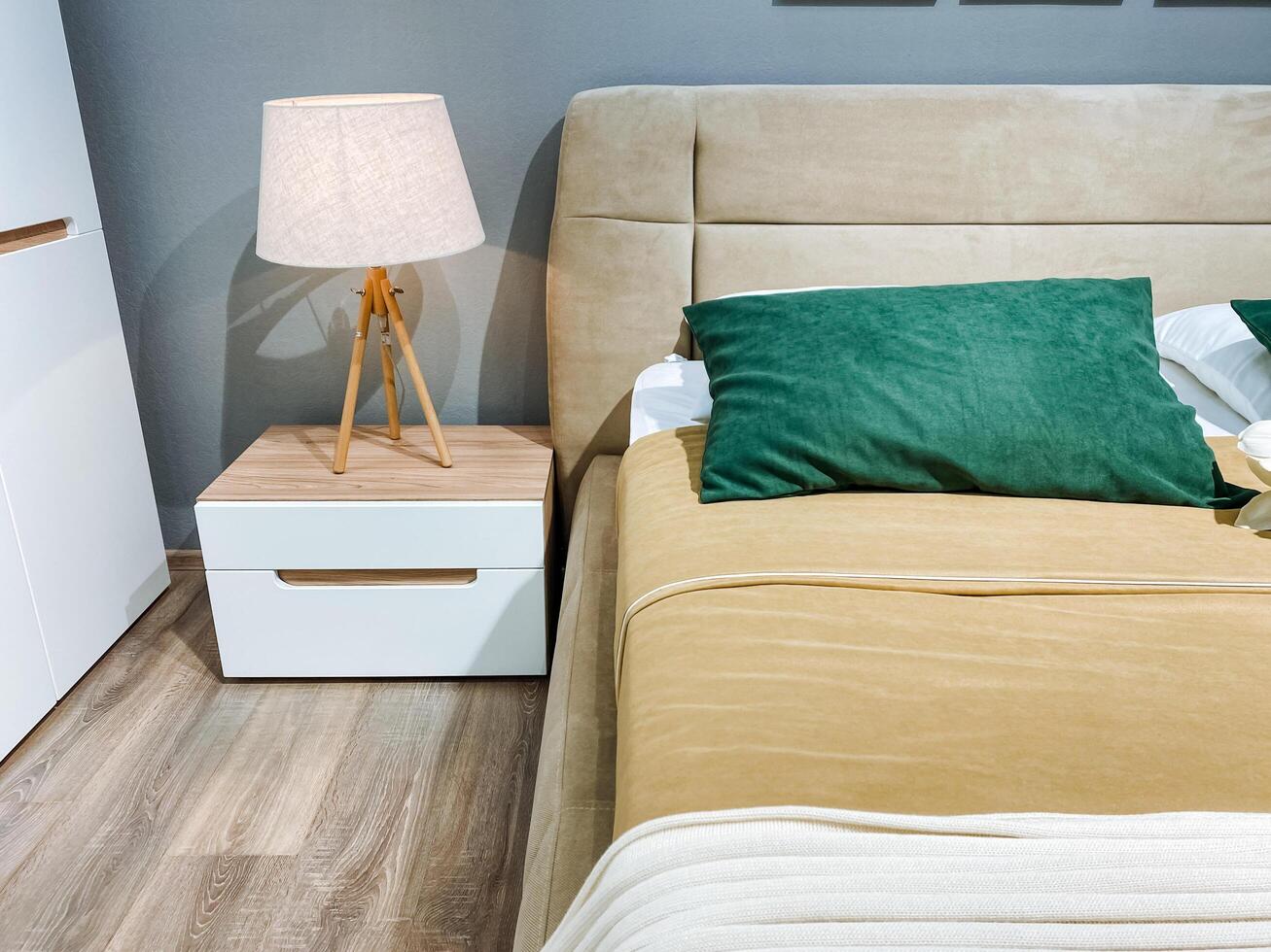 This cozy bedroom features a comfortable bed and a stylish nightstand. The warm lamp provides soft lighting, creating an ideal atmosphere for relaxation and restful sleep photo