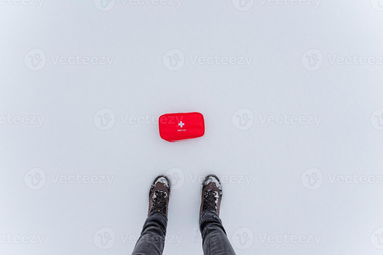 A person is standing in the cold snow next to a bright red box that contrasts with the white winter landscape around them, surrounded by freezing temperatures and precipitation photo