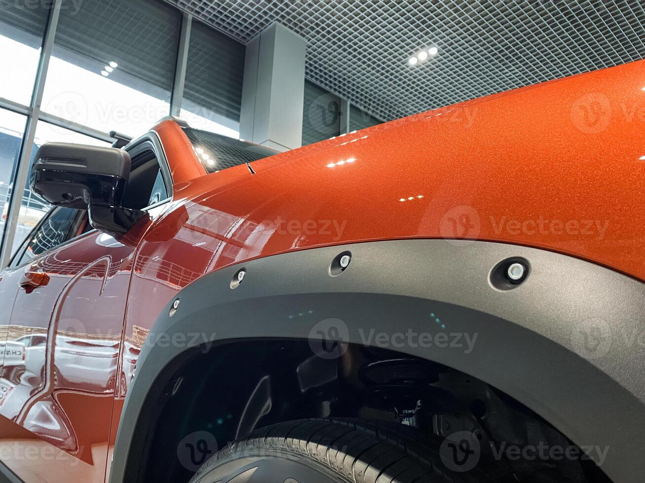 This image features a detailed closeup of a striking orange car that is prominently highlighted with stylish black fender flares, showcasing its impressive design and color contrast photo