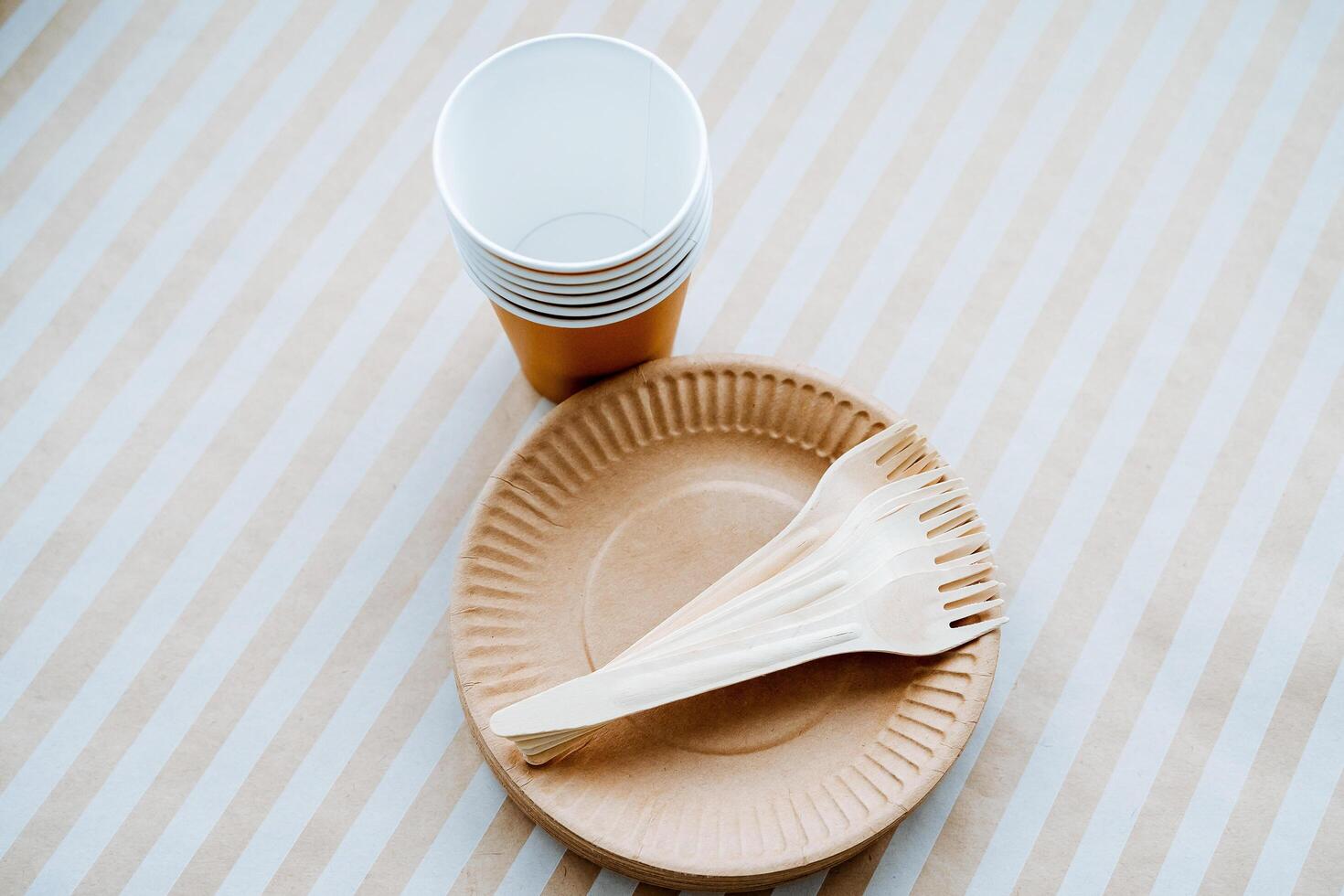 A simple paper plate featuring a fork and spoon carefully placed on top of it, situated right next to a cup. This setup creates a casual dining experience perfect for any gathering photo