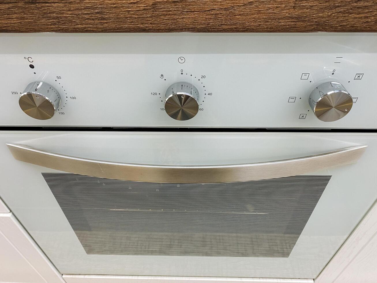 This elegantly designed white oven features shiny silver knobs and a stylish glass door, making it a perfect addition to any modern kitchen space with functionality and aesthetic appeal photo