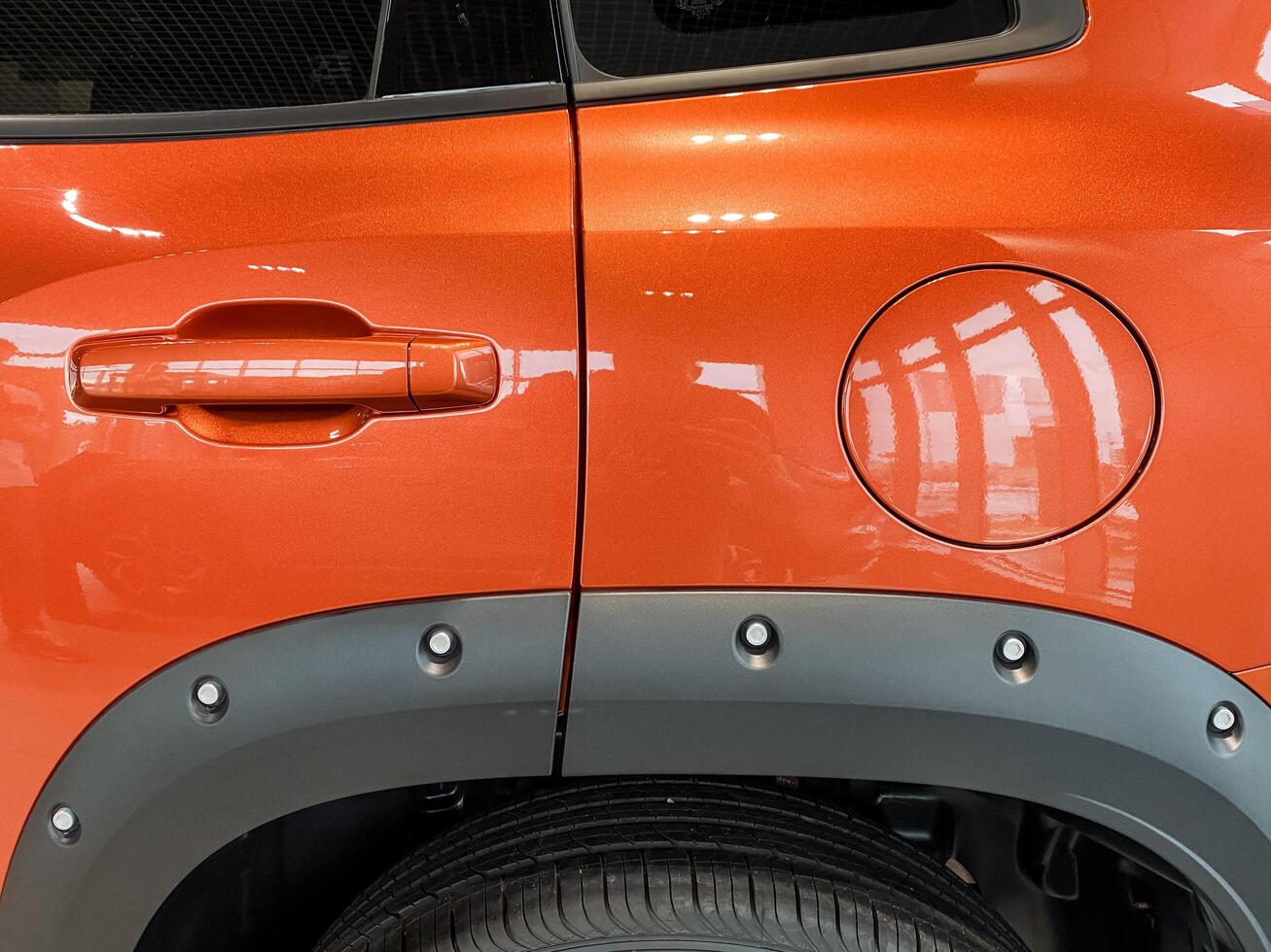 A closeup of an orange car highlights its side gas cap, showcasing a design that effectively combines functionality with aesthetics and includes various automotive features photo