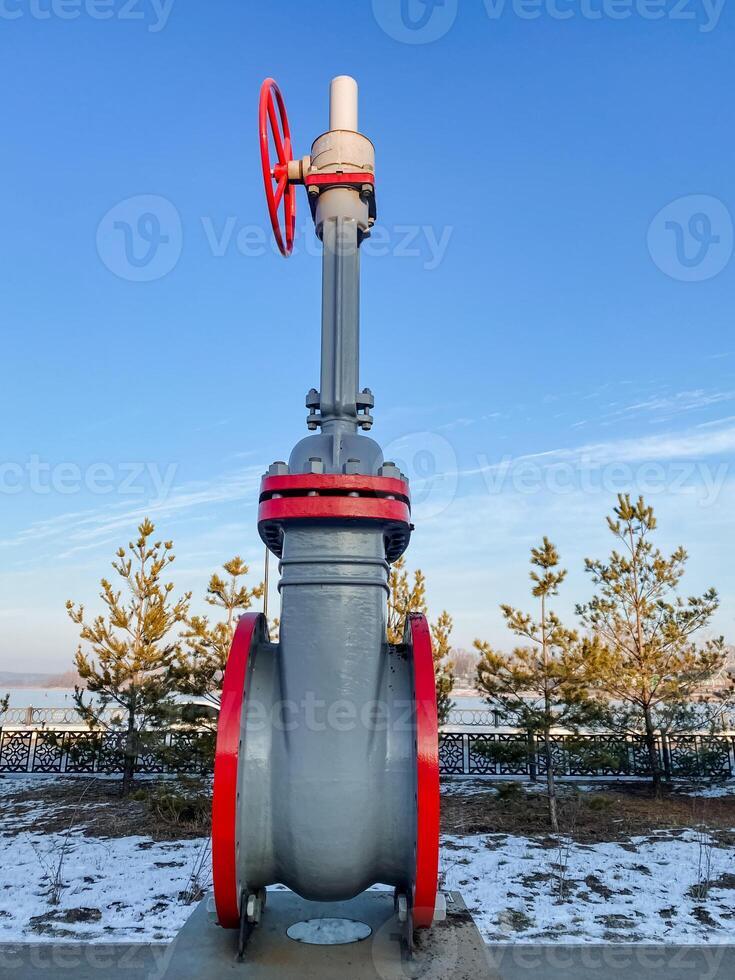 A large valve, complete with a prominent red handle, is positioned on top of a solid concrete surface, creating a striking contrast to its surroundings and emphasizing its importance photo