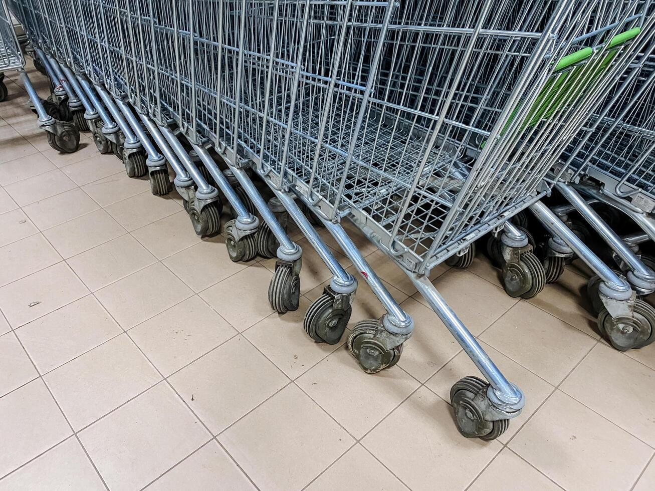 A long and orderly row of shopping carts is perfectly lined up on a clean, tiled floor within the store, ready for customers to easily grab and use for their shopping needs photo