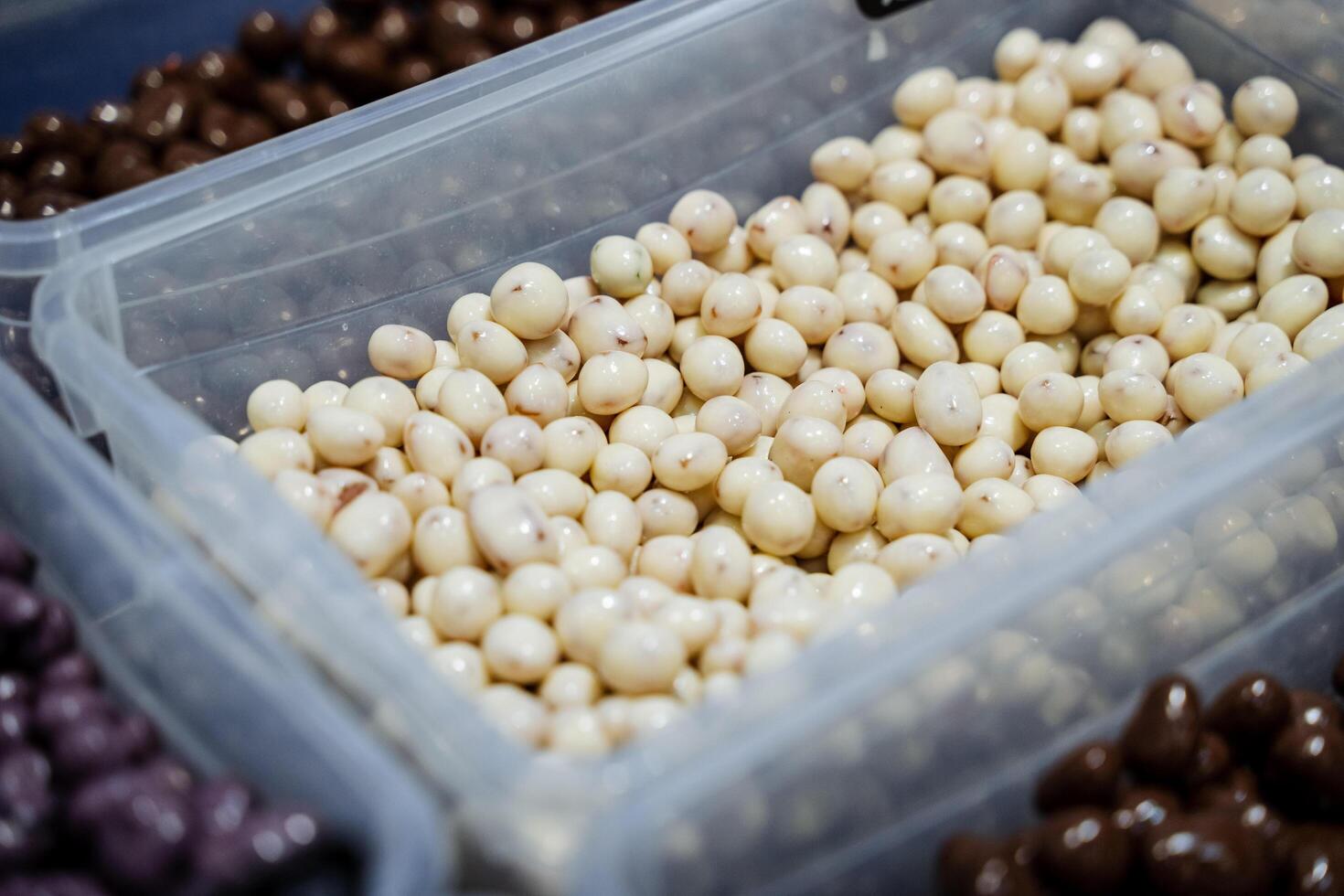 A detailed closeup image captures a clear plastic container filled with a delightful assortment of various nuts, showcasing their intricate textures and vibrant, appealing natural colors photo
