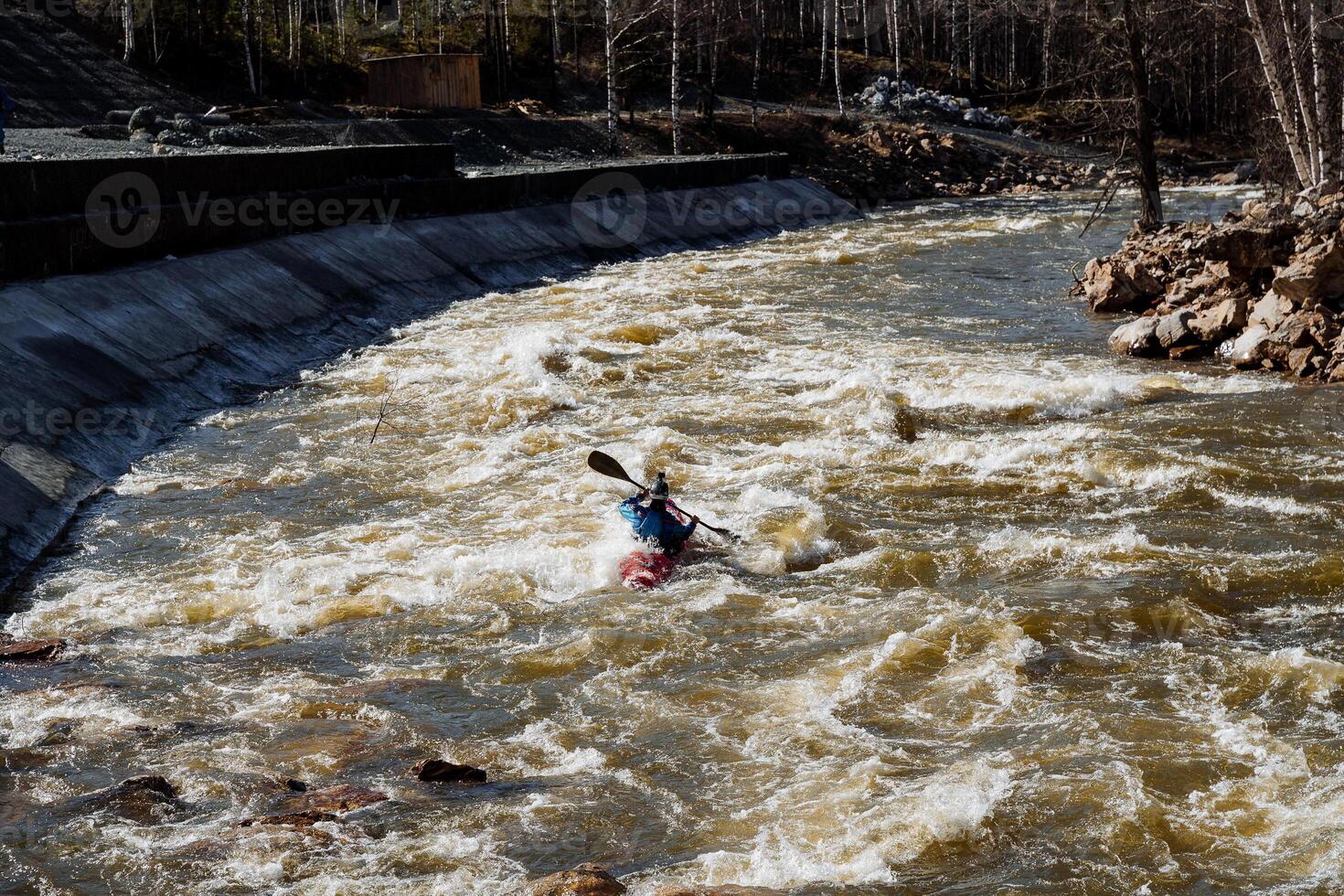 A person is energetically paddling a kayak through the flowing waters of a river, surrounded by the beautiful scenery, showcasing the joy of river kayaking and adventure in nature photo