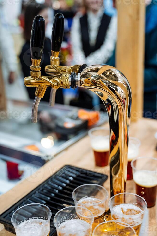 A beer tap steadily pours a frothy, delicious beer into glasses that sit ready on the table, patiently awaiting the arrival of people who will gather to celebrate in joy and camaraderie photo