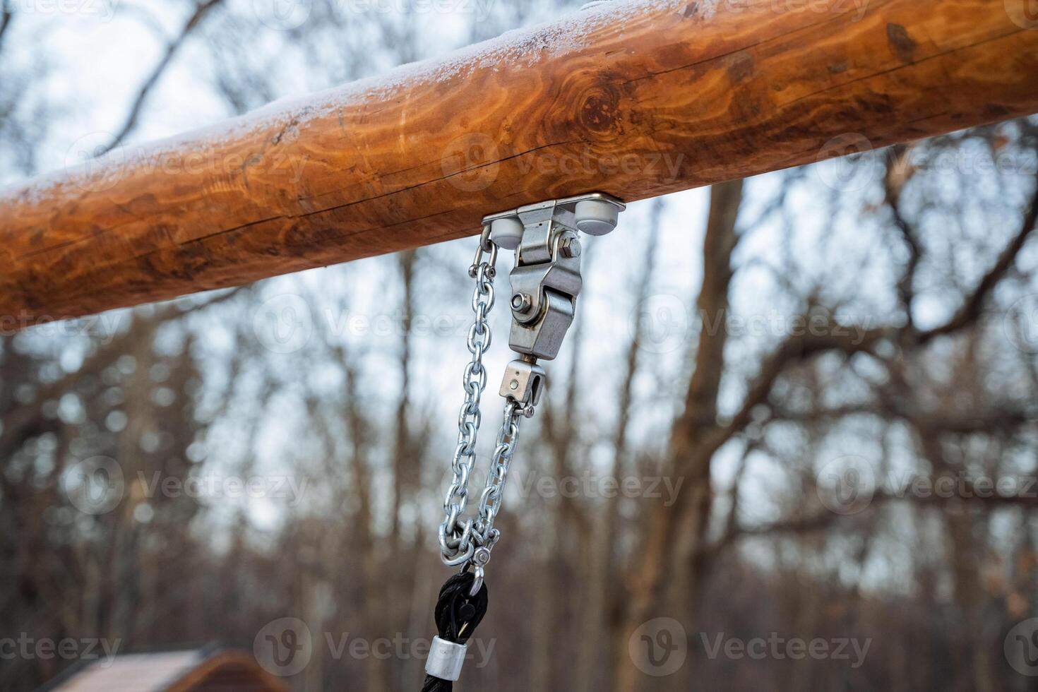 A detailed close up of a sturdy wooden pole that has a strong chain securely attached to it, showcasing the textures and the various elements surrounding it, creating a rustic scene photo