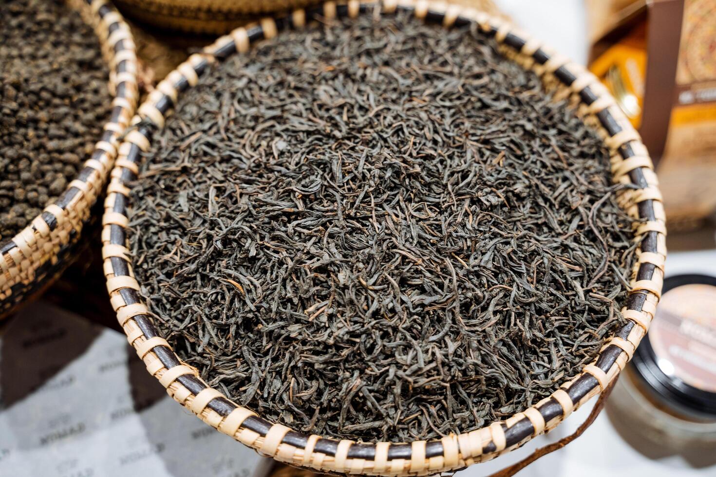 A beautifully crafted basket filled with aromatic black tea leaves rests on a rustic wooden table, showcasing rich tones and an inviting essence for admirers of natural ingredients photo