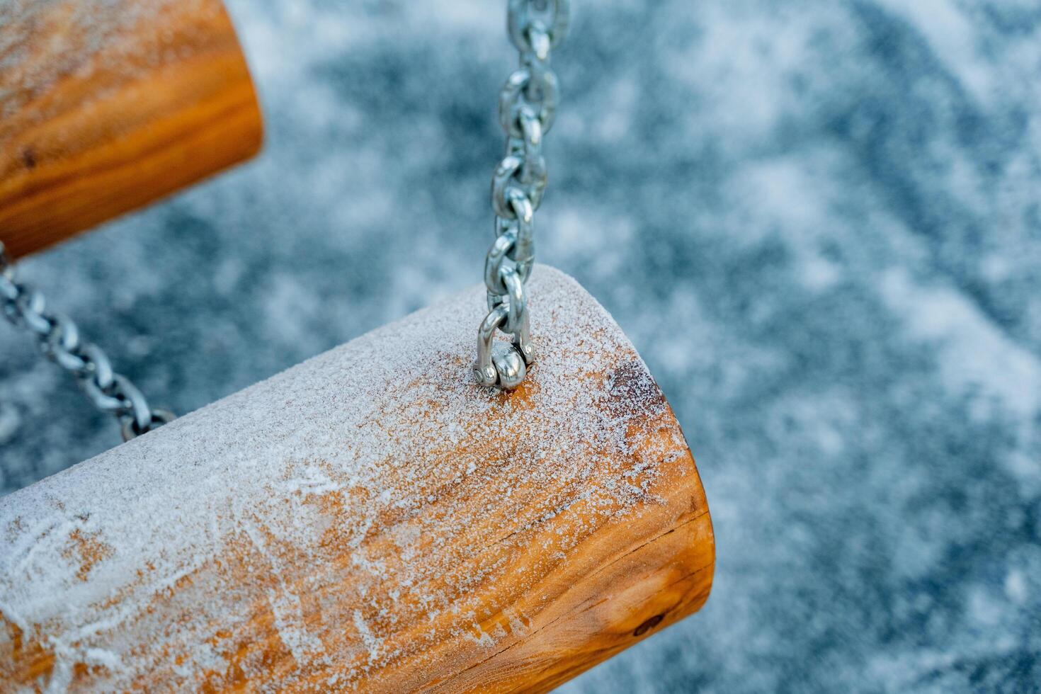 A beautiful wooden swing, complete with chains, is completely covered in a soft layer of white snow, creating a picturesque winter scene that invites playfulness and joy photo