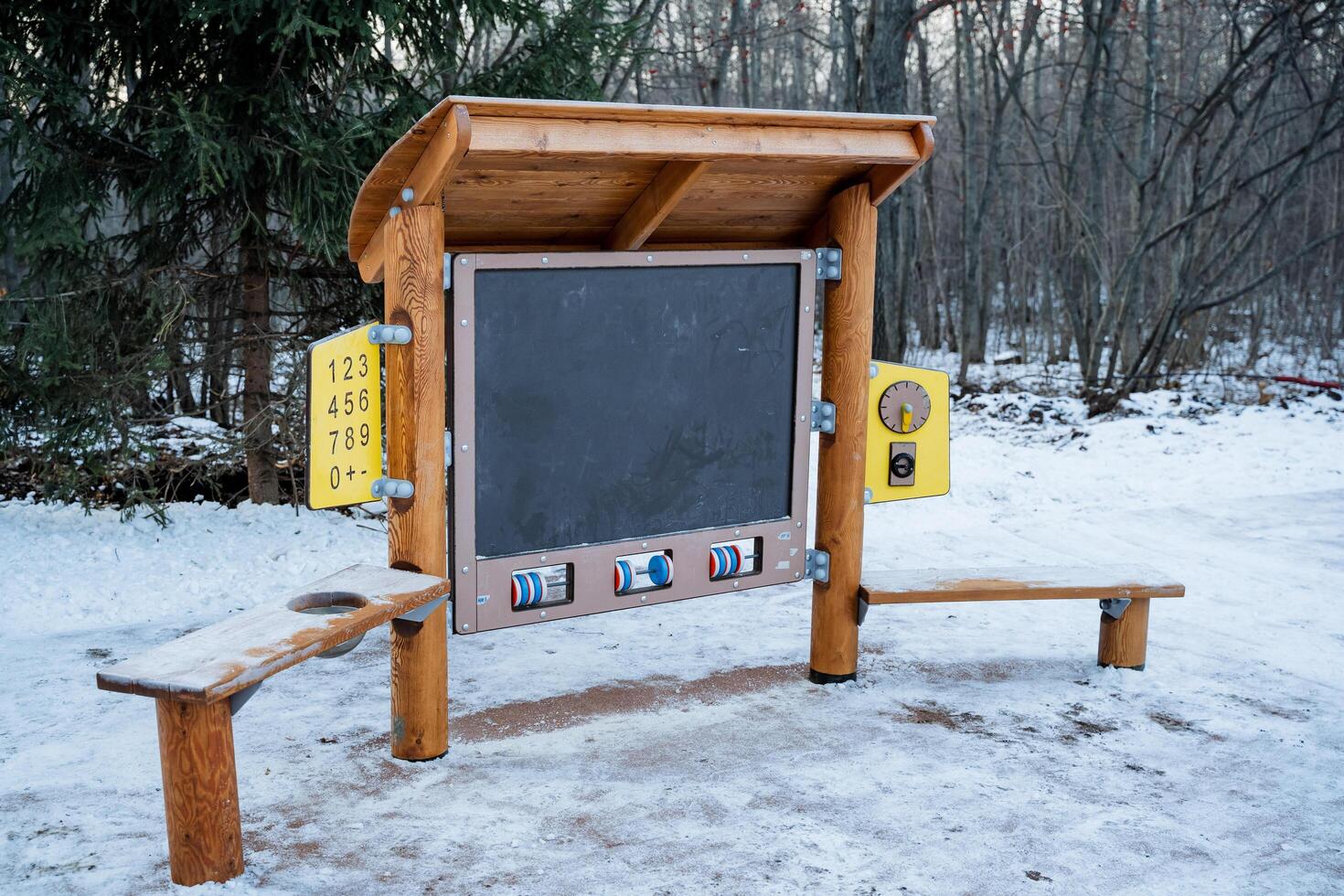 In the midst of the snowcovered landscape, there stands a charming wooden kiosk, complete with a chalkboard for messages and a cozy bench for sitting, creating a picturesque winter scene photo