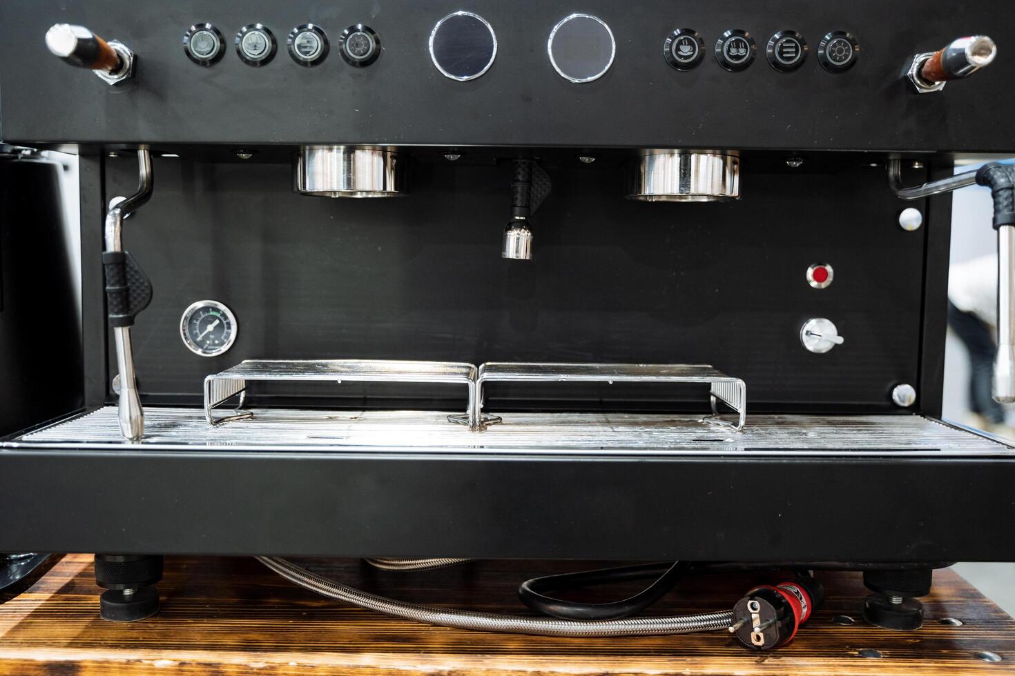 A sleek and modern black coffee machine is elegantly positioned on a rustic wooden table, creating an appealing contrast between the dark appliance and the natural wood grain surface photo