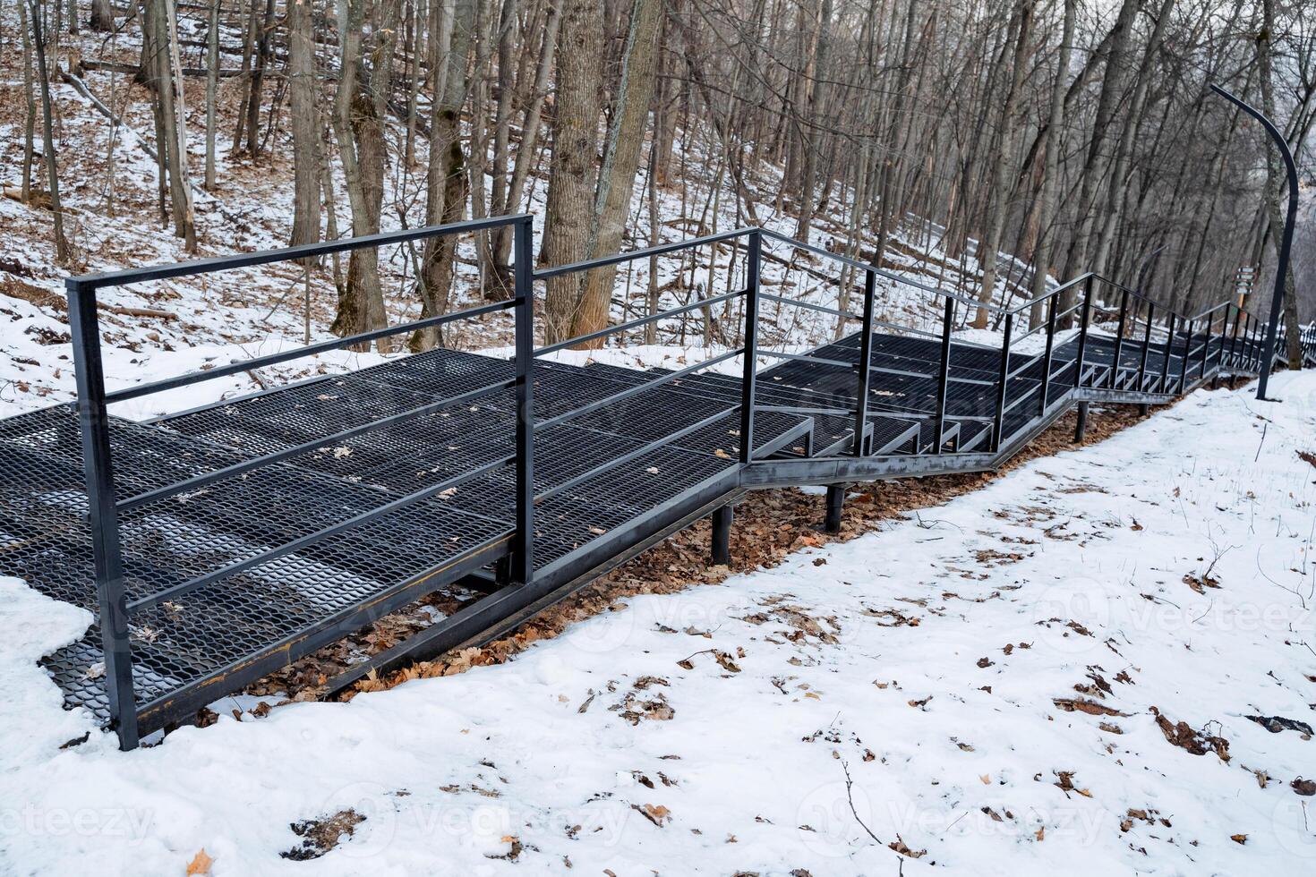 Winding Snowy Path with Sturdy Metal Railings in a Beautiful Forested Area This is a Scenic Winter Hiking Trail that invites adventurers to explore its serene beauty photo