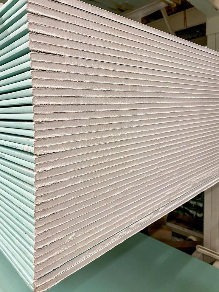 A stack of multiple drywall sheets arranged neatly and sitting on top of each other upon a sturdy table, demonstrating a common building material used in construction projects photo