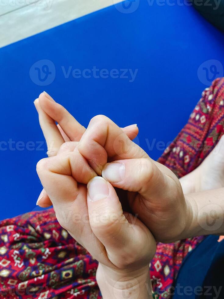 This image features a closeup view of a persons hands resting on a vibrant blue mat, showcasing intricate details such as fingers, gestures, and nails, along with the wrist area photo