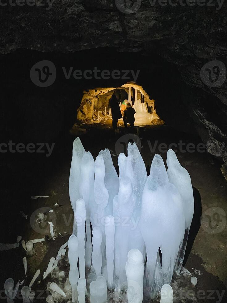 A group of individuals is making their way through an intriguing cave that features stunning ice formations all around them, creating a breathtaking and chilly atmosphere they explore photo