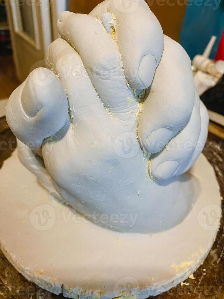 A beautifully crafted statue of two hands clasped together, elegantly placed on a polished wooden tabletop, showcasing exceptional artistry and captivating emotions for all viewers photo