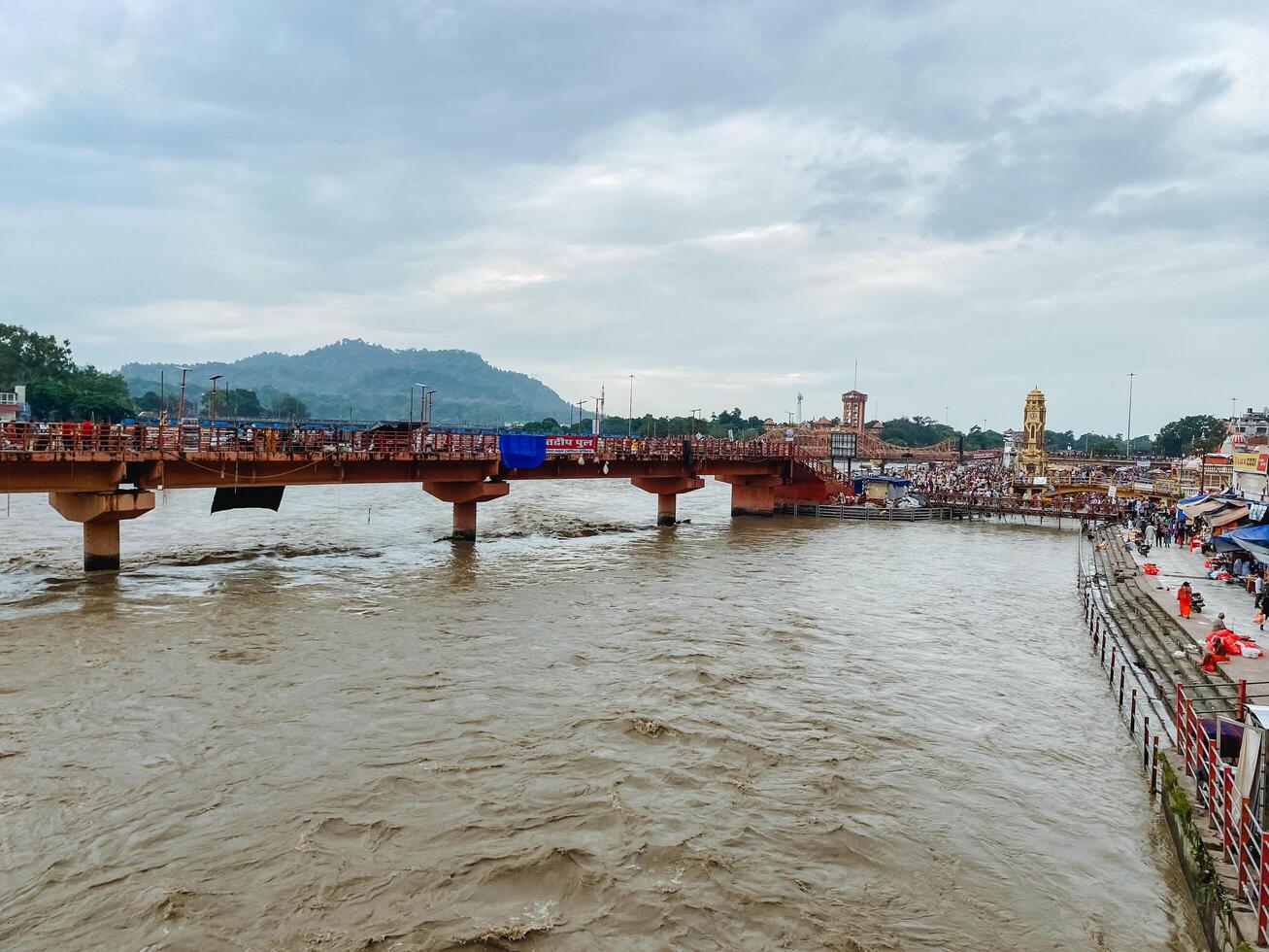 A magnificent and impressive bridge gracefully spans over a flowing river, while a bustling crowd of people gathers, engaging in the experience and enjoying the stunning view photo