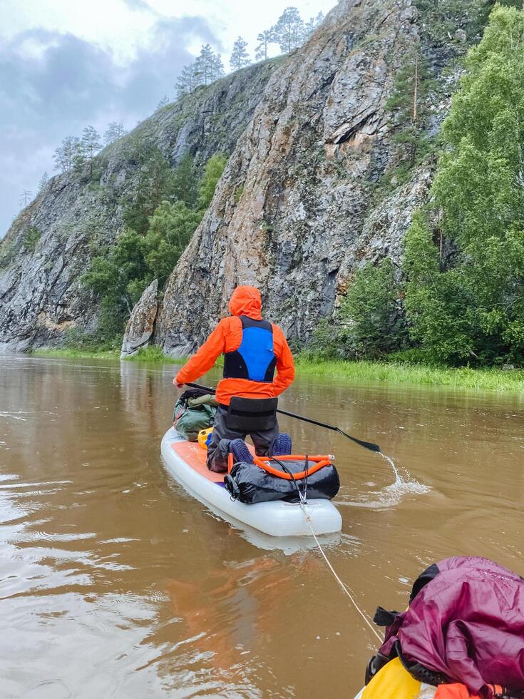 A man skillfully navigates his colorful kayak through a serene river, enjoying the peaceful atmosphere and stunning natural views on a sunny day, while engaging in the water sport photo