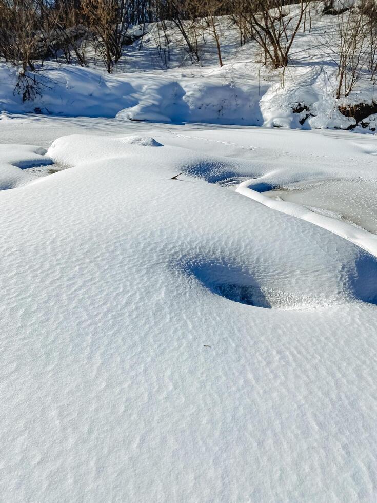 A vast, snowy field stretches out before you, dotted with trees in the background, creating a serene and picturesque winter landscape that captures the beauty of nature in its coldest form photo