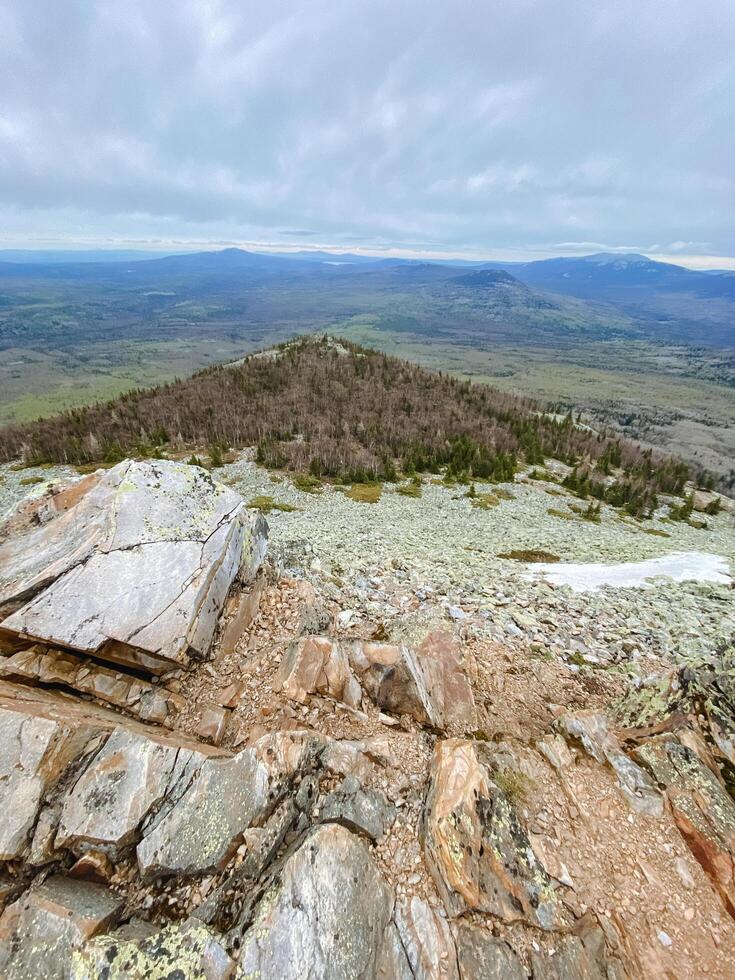 Standing atop a rugged hill provides an aweinspiring view of an astonishing mountain range, highlighting the stunning and magnificent beauty of nature that encompasses this rocky elevation photo