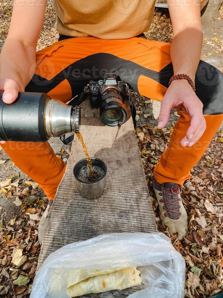 At this very moment, a person is actively pouring a liquid substance from a thermos container into a cup, which can be used for drinking or various other intended purposes photo
