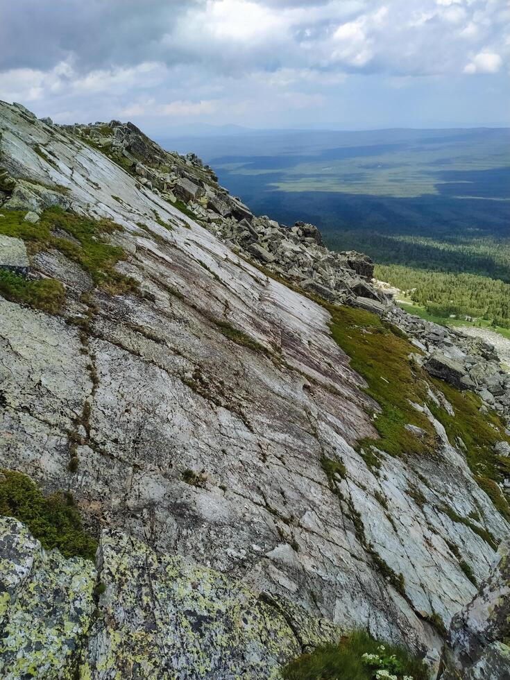 A majestic and towering mountain, beautifully adorned with rugged rocks and patches of lush green grass, creates a truly stunning and captivating natural landscape that inspires awe photo