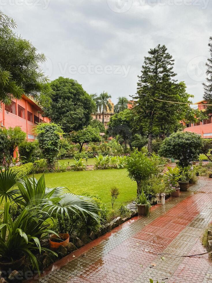 In a beautiful, lush green garden filled with vibrant foliage, there stands a striking red building prominently in the background, creating a stunning visual contrast amid nature photo