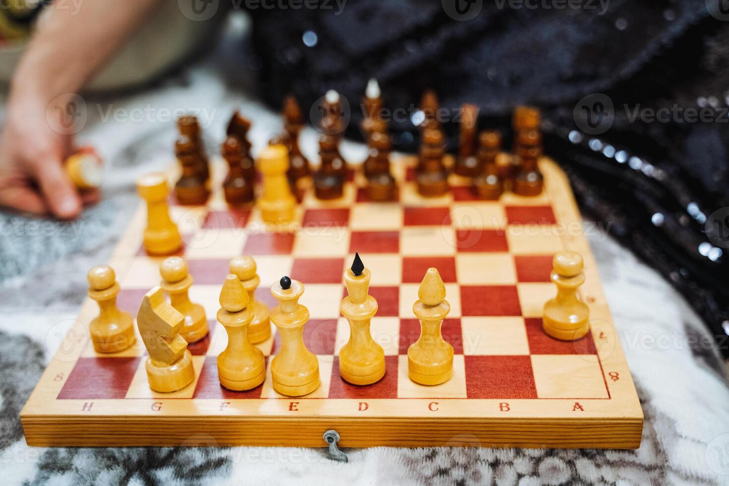 A person is actively engaged in playing a game of chess on a beautifully crafted wooden chess board, focusing intently on their next strategic moves and decisions in the game photo