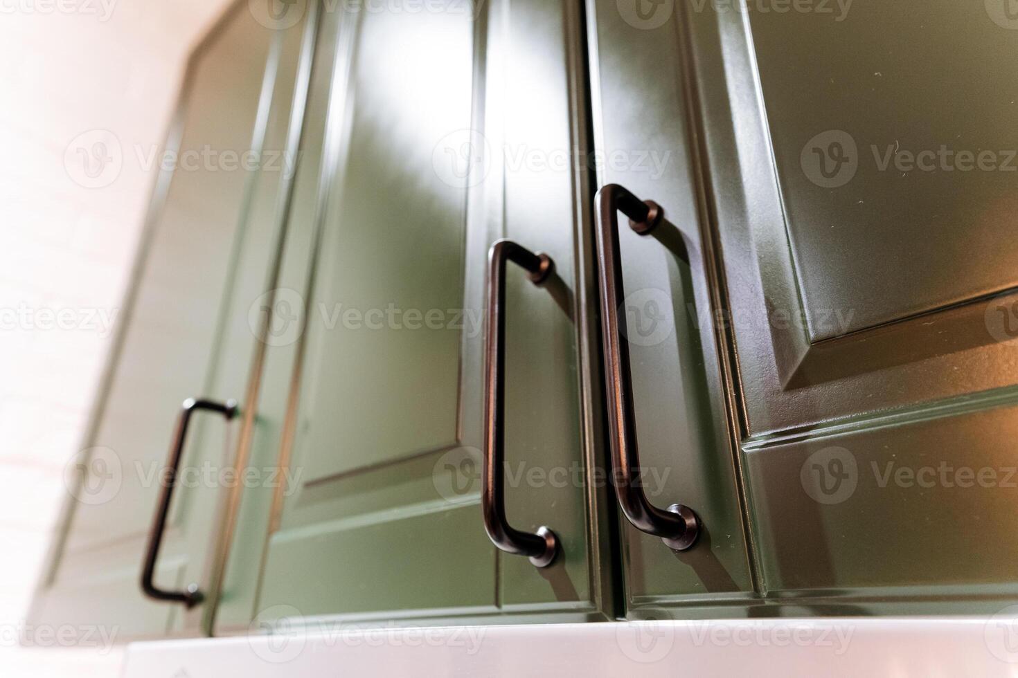 This image captures a detailed closeup view of vibrant green cabinets, elegantly complemented by sleek black handles that highlight their modern design and functionality photo