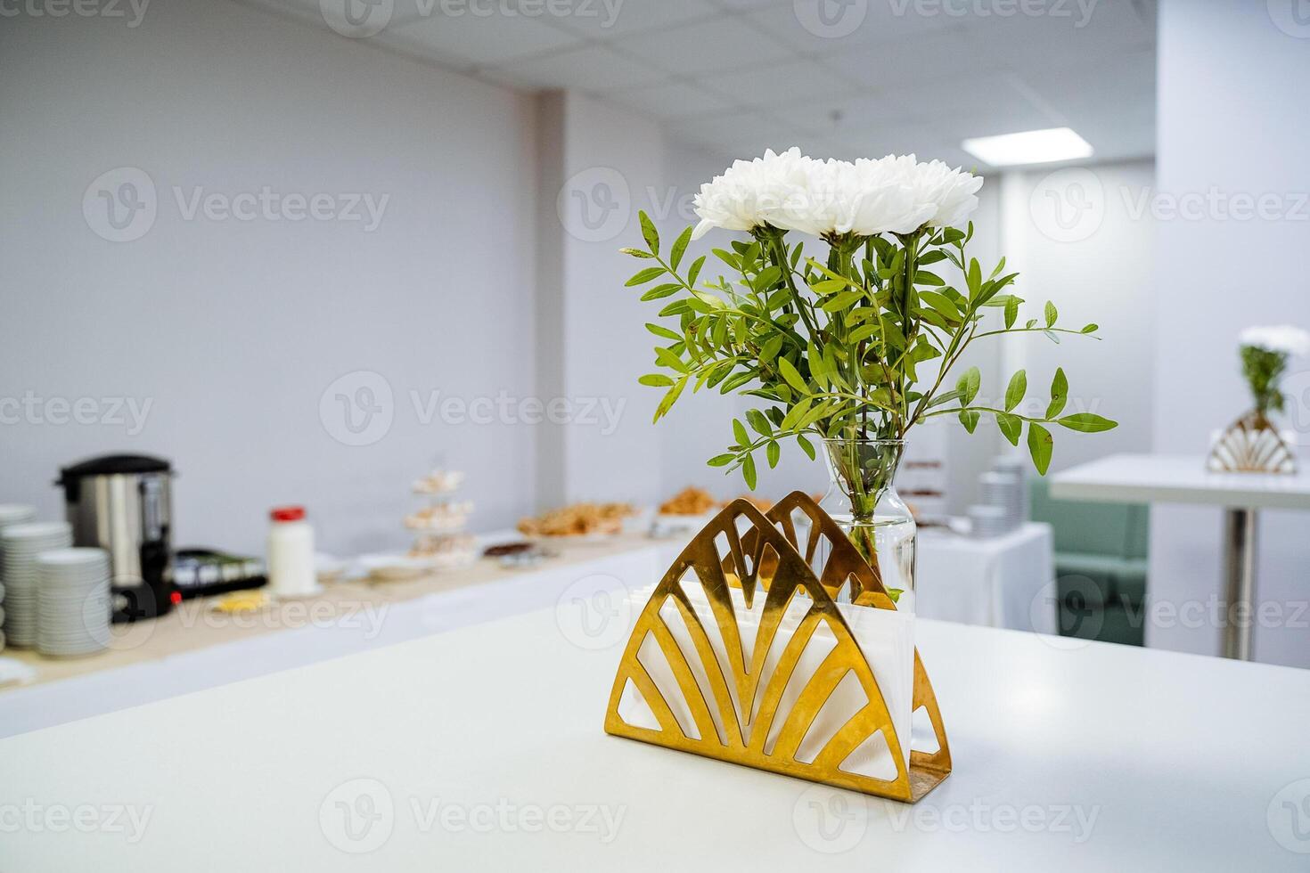 On a sturdy wooden table, a beautiful vase filled with vibrant flowers gracefully sits next to an elegant napkin holder, creating a charming and inviting atmosphere in the room photo