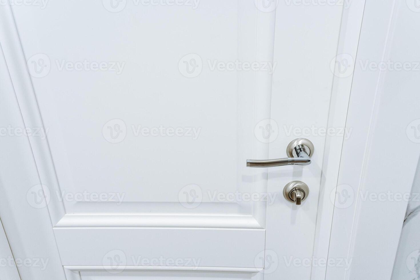 This image features a detailed closeup view of a pristine white door, complemented by a sleek, shiny silver handle that adds an elegant touch to the overall design of the door photo