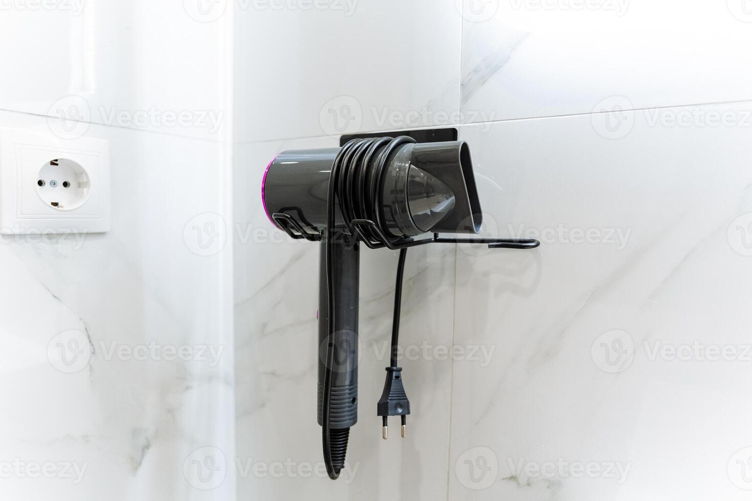 In the bathroom, a hair dryer is conveniently hanging on the wall, providing easy access for users who want to style their hair quickly and efficiently while getting ready photo