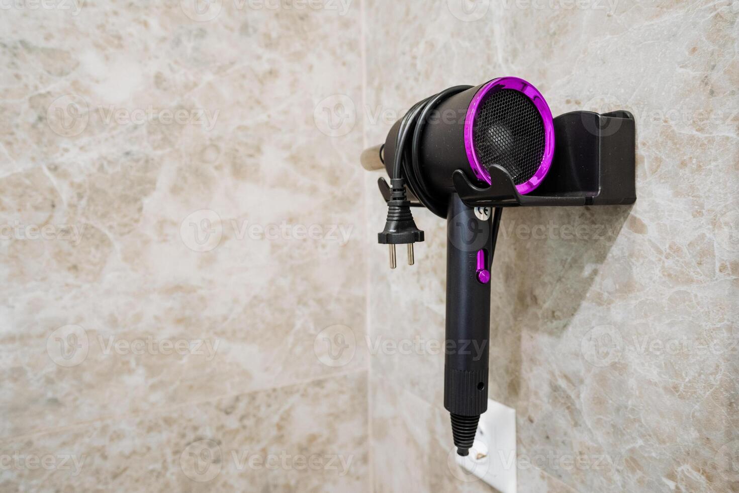 A hair dryer is securely hanging on the wall in a bathroom, which is a common sight in many homes and establishments, providing convenience for users who need to style their hair photo
