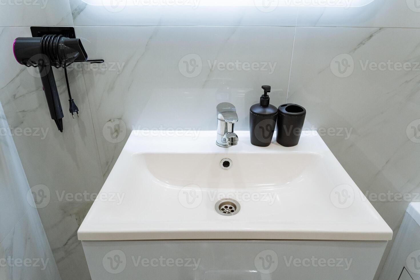 In the bathroom, there is a sink beautifully integrated with a hair dryer that is conveniently hanging on the wall nearby, making it easy to access while preparing for your day photo