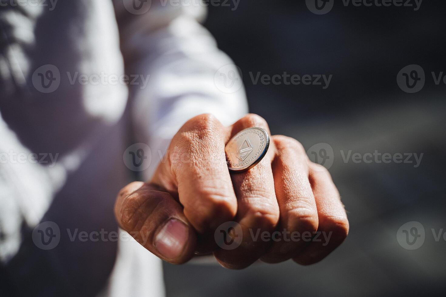 A person confidently holds a shiny, gleaming coin in their hand, drawing attention to the beautifully manicured fingers and thumb, showcasing a fascinating interplay with their wrist photo